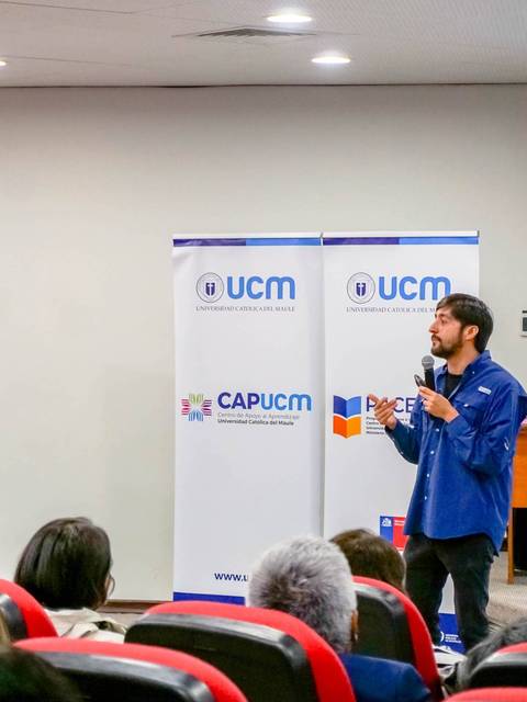 Un hombre da una charla mientras un grupo de personas lo escucha en un salón.