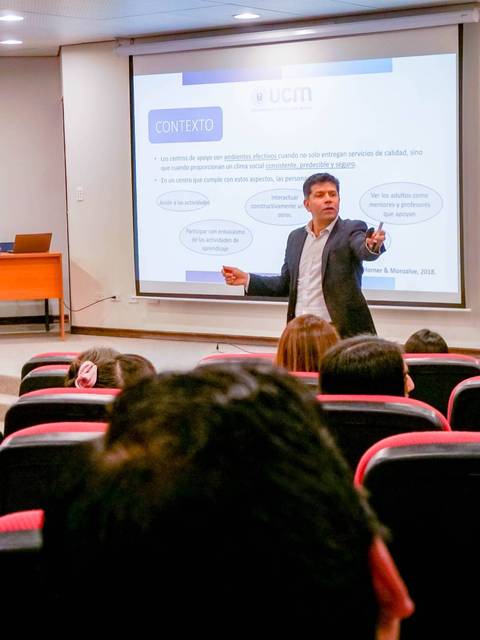 Un presentador está dando una conferencia frente a un auditorio lleno de personas.