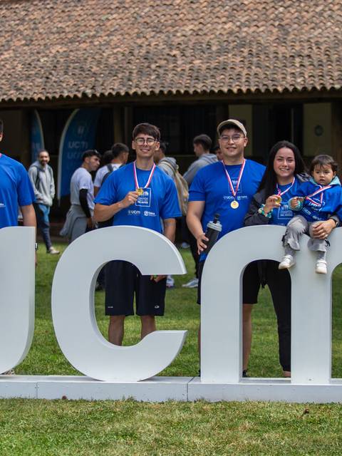 Grupo de personas sonrientes vestidos con camisetas azules junto a un letrero grande que dice 'ucm'.