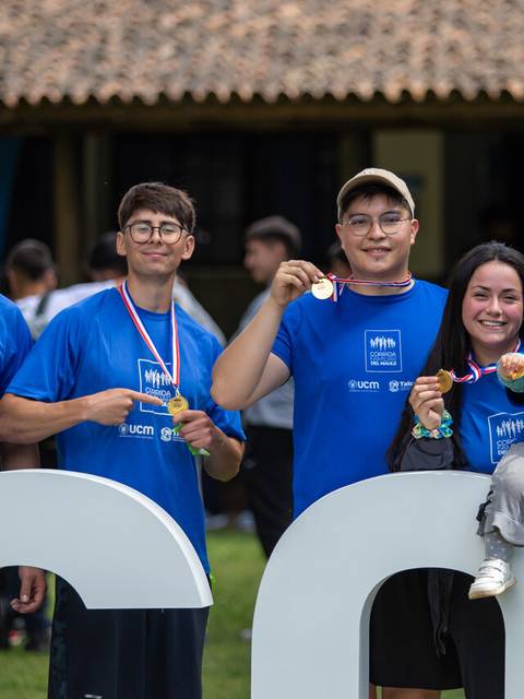 Grupo de personas sonrientes con medallas en un evento al aire libre.