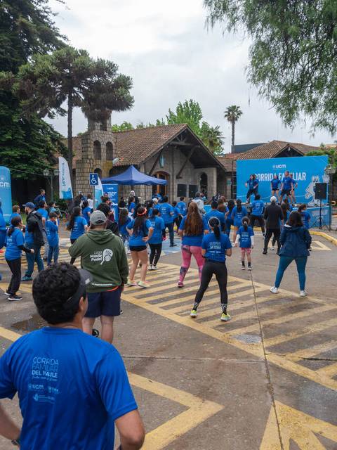 Un grupo de personas se reúne para hacer ejercicio al aire libre, todos vistiendo camisetas azules.