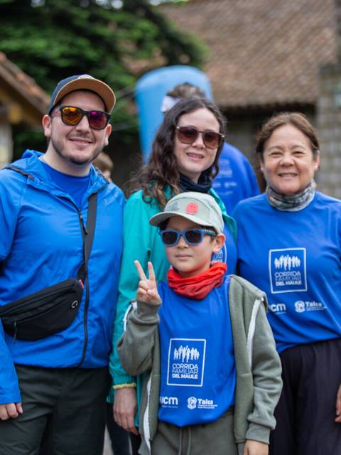 Un grupo de cuatro personas posando juntas en un evento exterior, todas vistiendo camisetas azules.