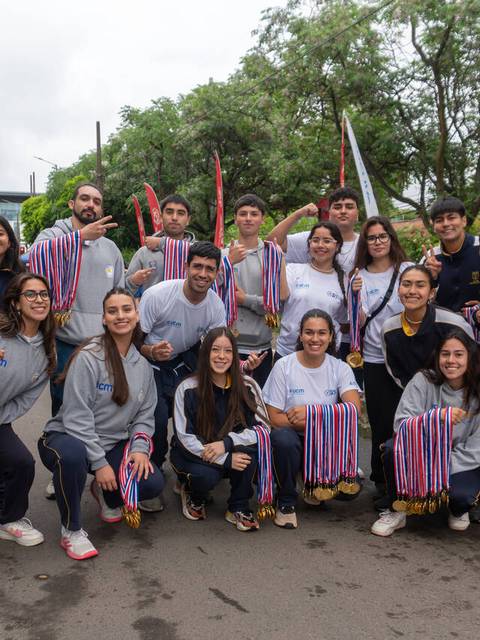 Grupo de jóvenes sonrientes sosteniendo medallas después de un evento deportivo.