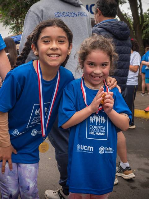Dos niñas sonrientes posan con medallas después de una carrera.