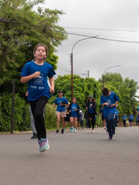 Un grupo de personas corre por una calle rodeada de vegetación.