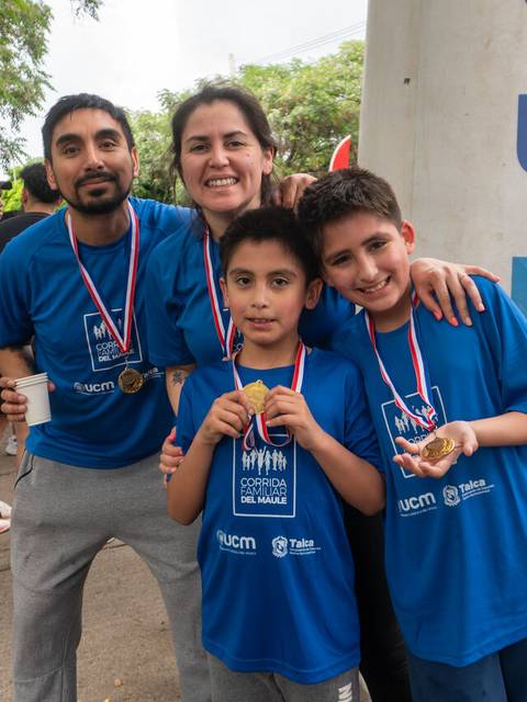 Un grupo de cuatro personas sonrientes, vestidas con camisetas azules, posando después de una carrera.