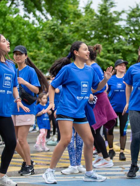 Un grupo de niños y adolescentes bailando durante un evento al aire libre, todos vestidos con camisetas azules.