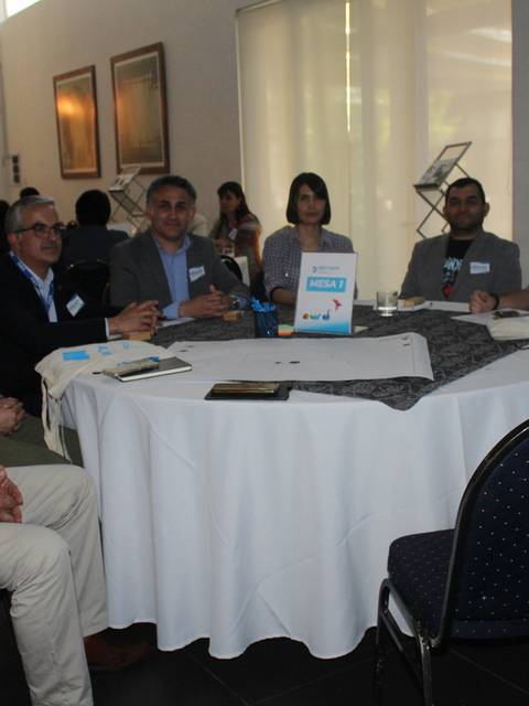 Un grupo de personas sentadas alrededor de una mesa en un ambiente de reunión o conferencia.