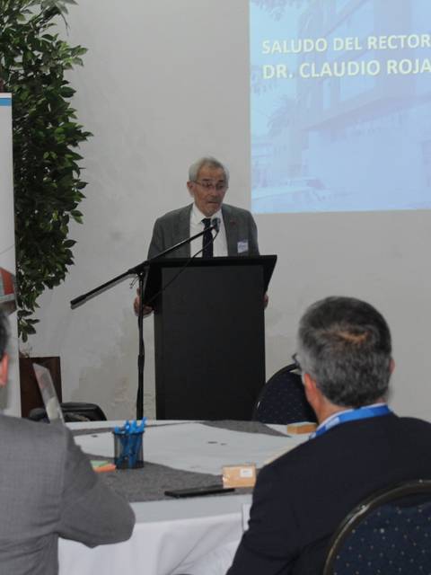 Un hombre está hablando en un evento frente a un grupo de personas sentadas en una mesa.