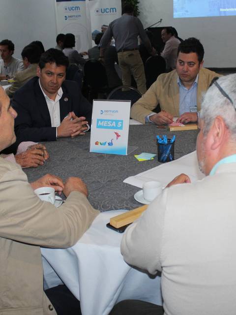 Un grupo de profesionales discutiendo en una mesa de trabajo durante un evento.