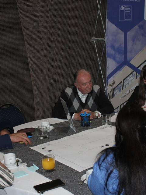 Un grupo de personas discutiendo alrededor de una mesa en un ambiente de trabajo.