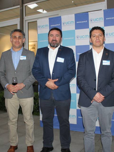 Un grupo de cinco personas posando delante de un fondo con el logo de UCM.