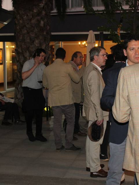 Un grupo de hombres hablando en un ambiente al aire libre durante una reunión social.