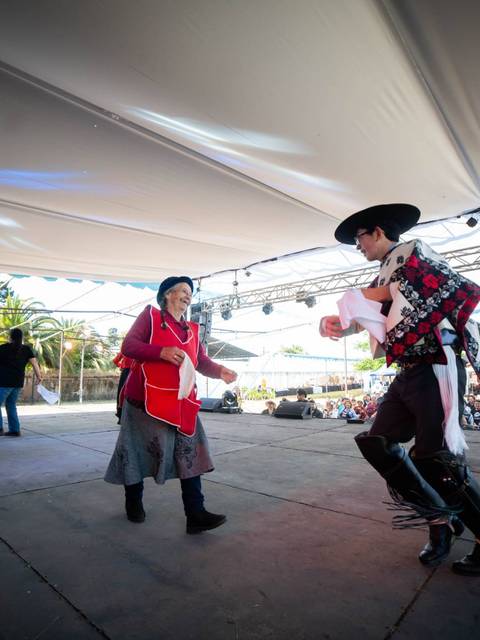 Una representación artística con personas bailando en un escenario al aire libre.
