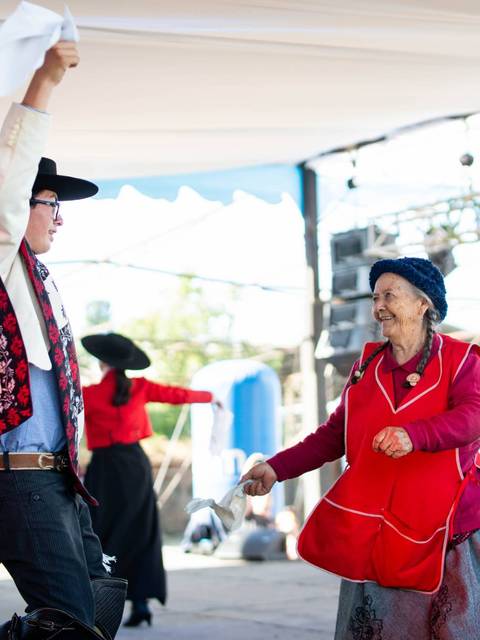 Un grupo de personas bailando tradiciones folclóricas en un escenario al aire libre.