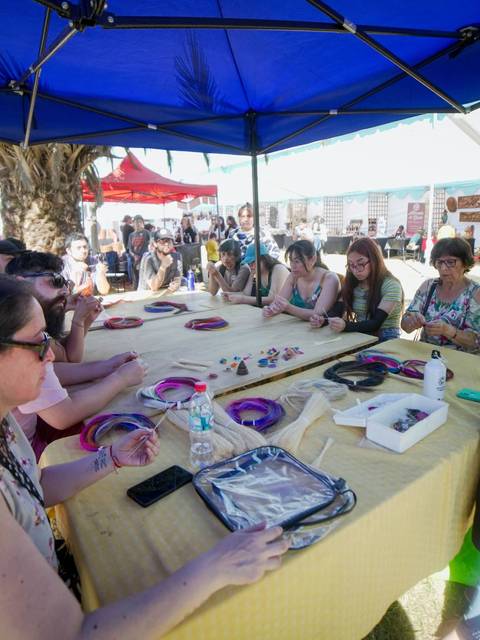 Un grupo de personas escucha atentamente a una instructora durante una actividad al aire libre bajo una carpa.