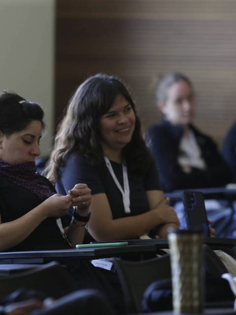 Un grupo de personas sentadas en una sala, prestando atención a una presentación o charla.