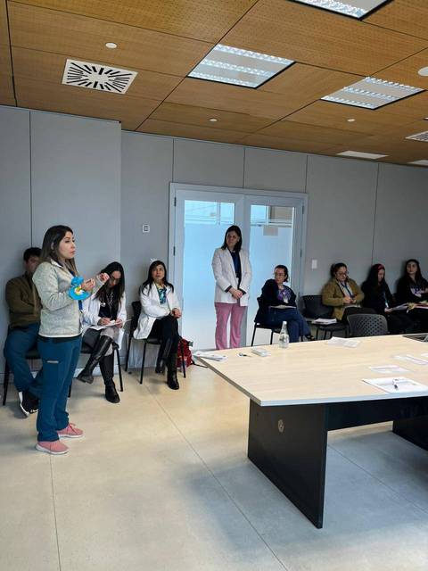Un grupo de profesionales de la salud participa en una reunión o presentación en un espacio moderno.