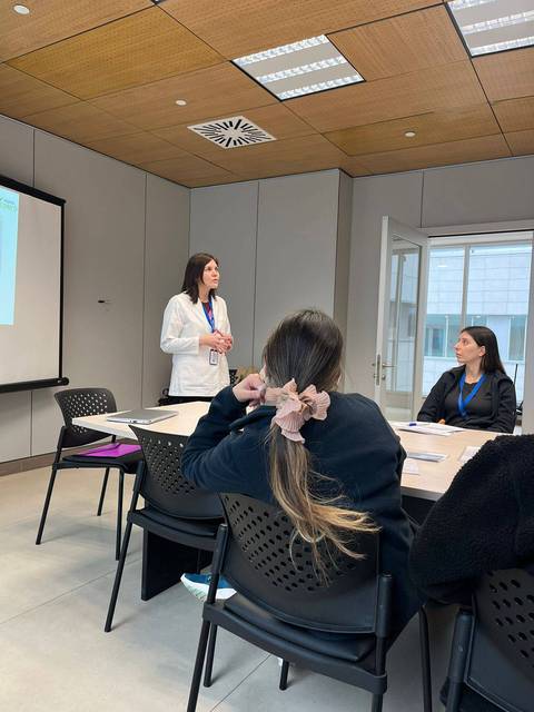 Una mujer está dando una presentación en una sala de reuniones mientras otras personas la escuchan.