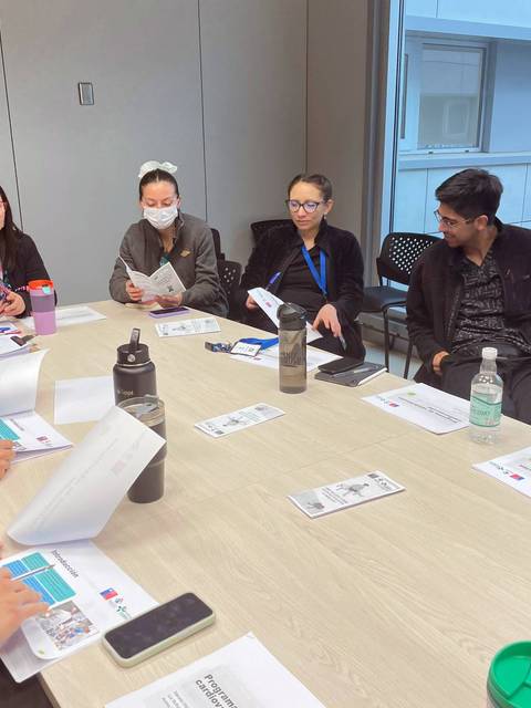 Un grupo de personas se encuentra en una reunión alrededor de una mesa con documentos en mano.