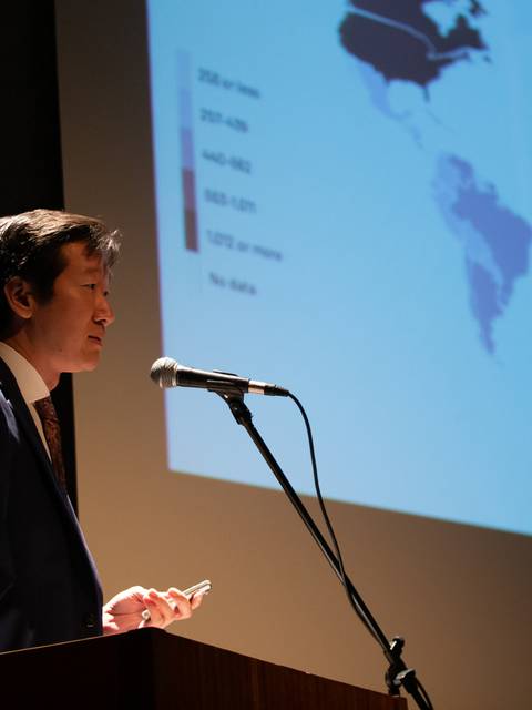 Un hombre habla en un podio frente a una pantalla con un mapa del mundo.