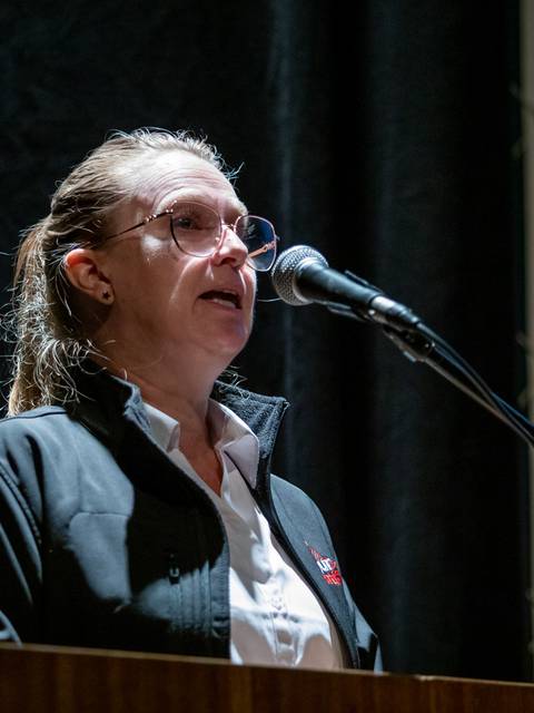 Una mujer habla en un micrófono durante un evento en un escenario.