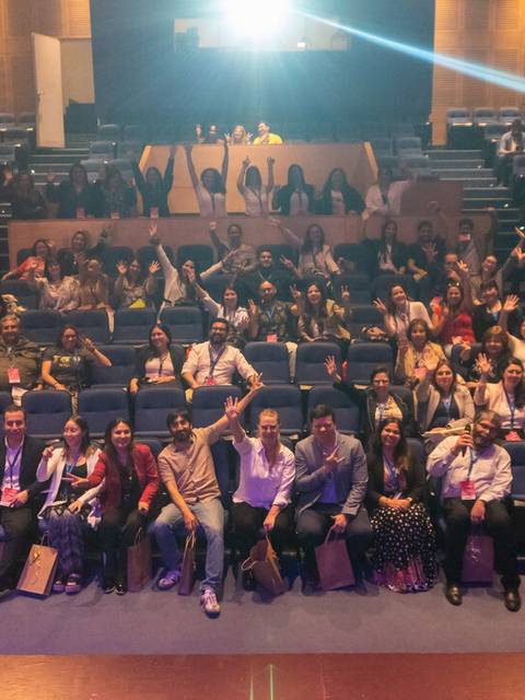 Un grupo de personas posando en un auditorio con asientos vacíos.