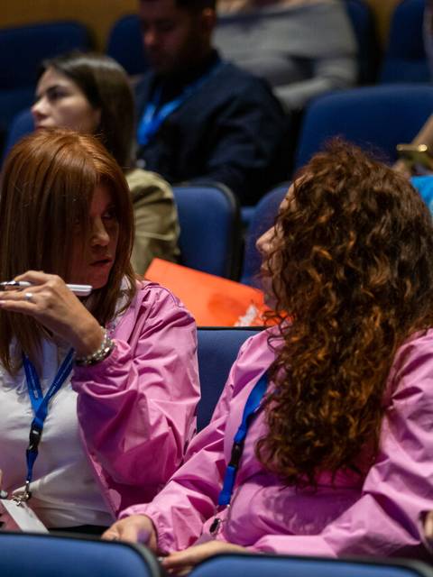 Un grupo de personas conversando en un auditorio durante un evento.