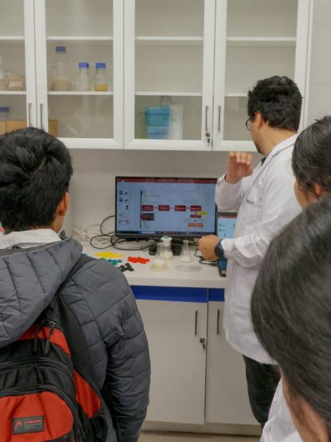 Un grupo de estudiantes observa a un docente mientras trabaja en un laboratorio.