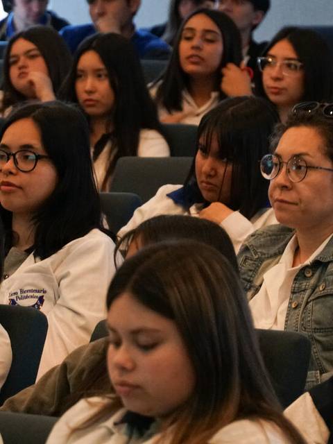 Un grupo de jóvenes y adultos escuchando atentamente en un evento.
