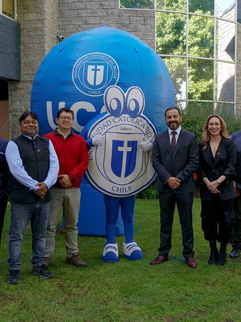 Un grupo de personas posa junto a una mascota y un edificio en un ambiente campestre.