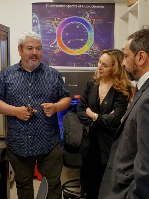Tres personas dialogan en un laboratorio de investigación científica.
