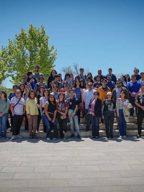 Un grupo numeroso de personas posando al aire libre bajo un cielo despejado.