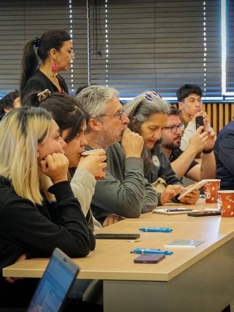 Un grupo de personas presta atención durante una charla en un aula.