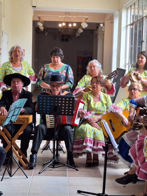 Un grupo de personas vestidas con trajes tradicionales se reúne para tocar música en un espacio iluminado.