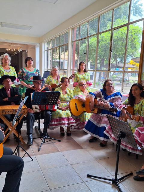 Un grupo de músicos con trajes coloridos toca instrumentos en un pasillo bien iluminado.