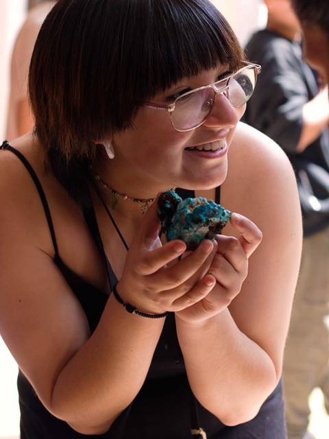Una mujer sonriente sostiene una piedra en sus manos, mostrando su entusiasmo.