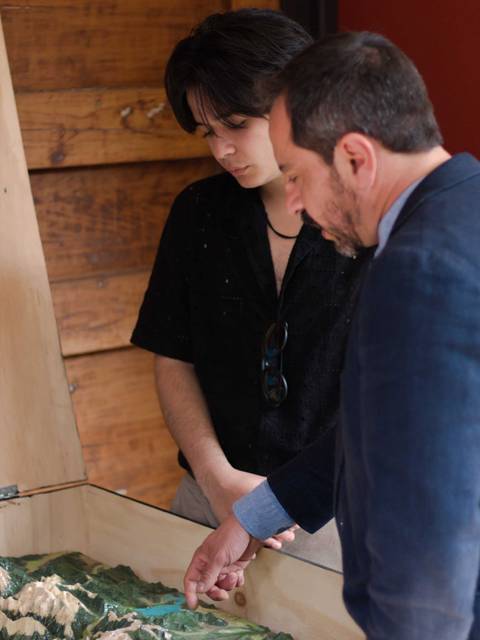 Dos personas observan un modelo topográfico en una mesa.