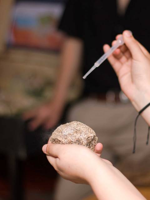 Una persona sostiene una piedra mientras utiliza un gotero.