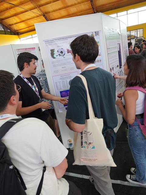 Un grupo de estudiantes interactúa con un expositor en un evento académico.