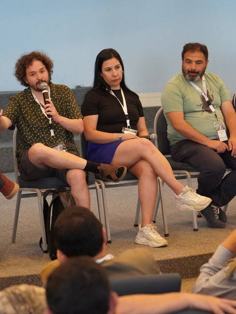 Un grupo de personas sentadas en un panel discutiendo en un evento.