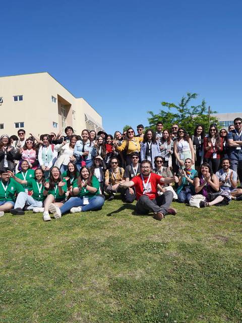 Un grupo grande de personas posando juntas al aire libre con un cielo despejado.