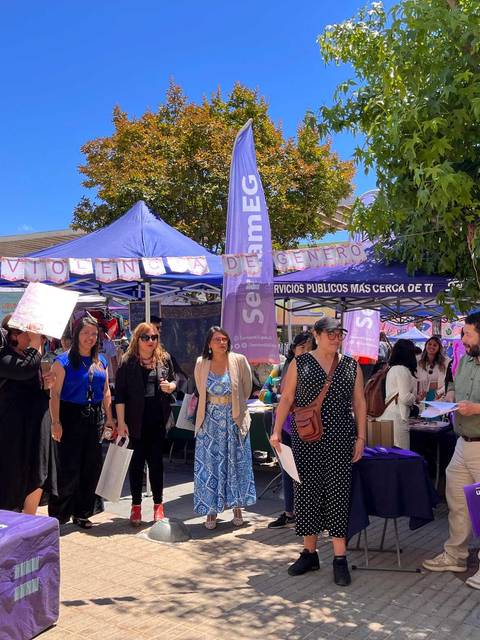 Un grupo de personas participando en un evento al aire libre rodeado de carpas y pancartas que promueven la prevención de la violencia.