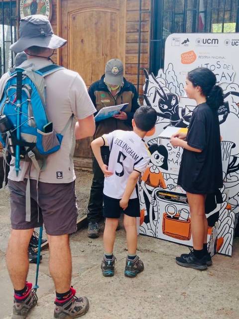 Un grupo de personas está interactuando con un cartel en un entorno natural.