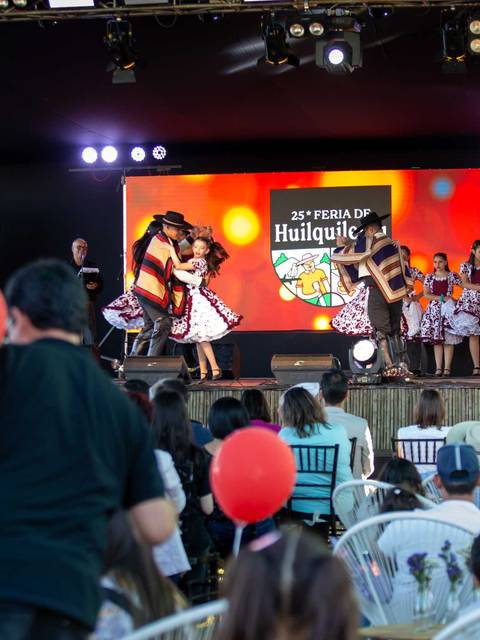 Una presentación cultural en un festival con bailarines en trajes tradicionales sobre un escenario.