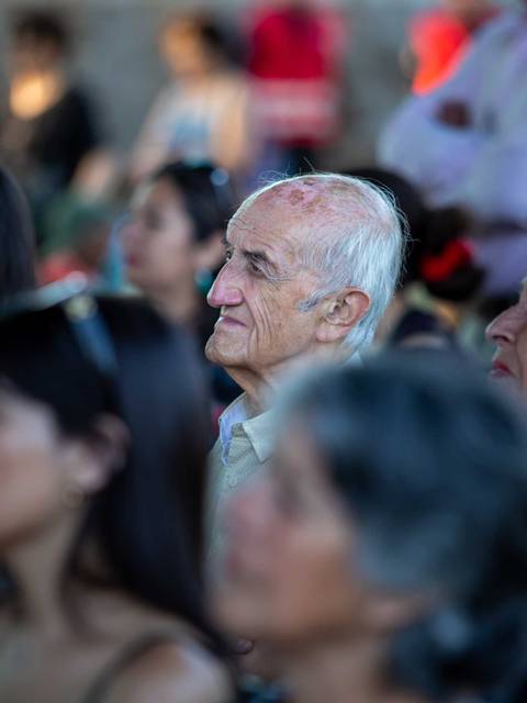 Una multitud de personas observa atentamente un evento en un espacio iluminado.
