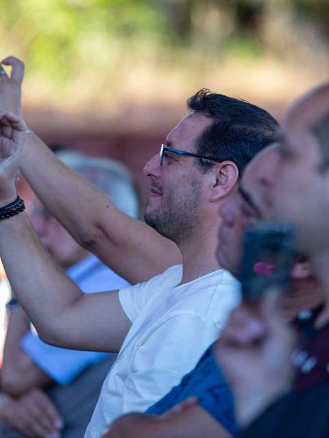 Un grupo de personas observa un evento mientras algunos graban con sus teléfonos móviles.