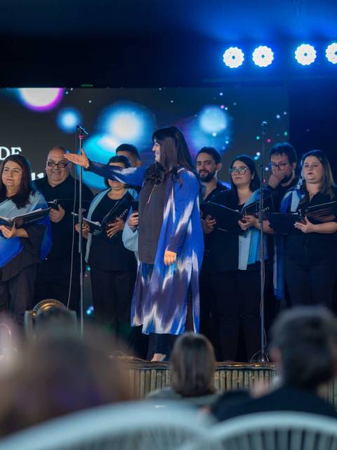 Un coro de personas cantando en un escenario durante un evento.