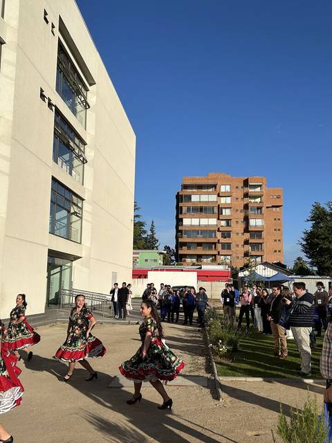 Un grupo de personas baila en el exterior de un edificio moderno durante un evento comunitario.