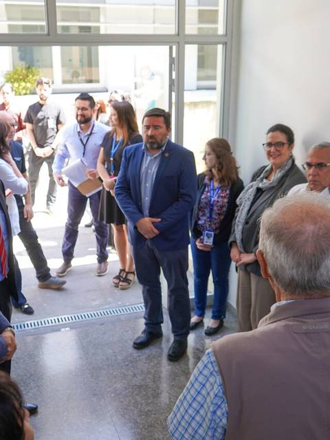 Un grupo de personas conversando en un pasillo, con algunos asistentes en un evento formal.